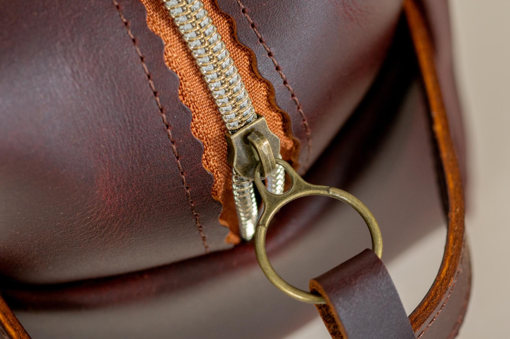 Close-up of Indigo Laine The Toiletry Kit in Tobacco, showing the scallop zipper and strong leather handle