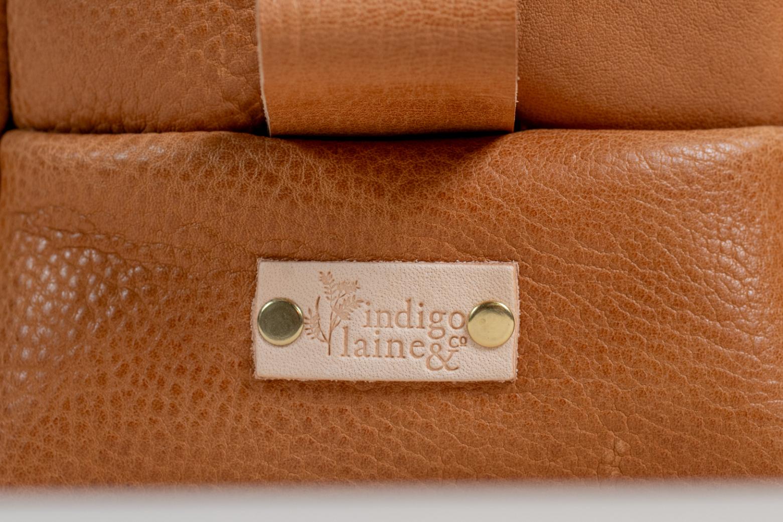 Close-up of Indigo Laine The Toiletry Kit in Camel, showing the Indigo Laine logo