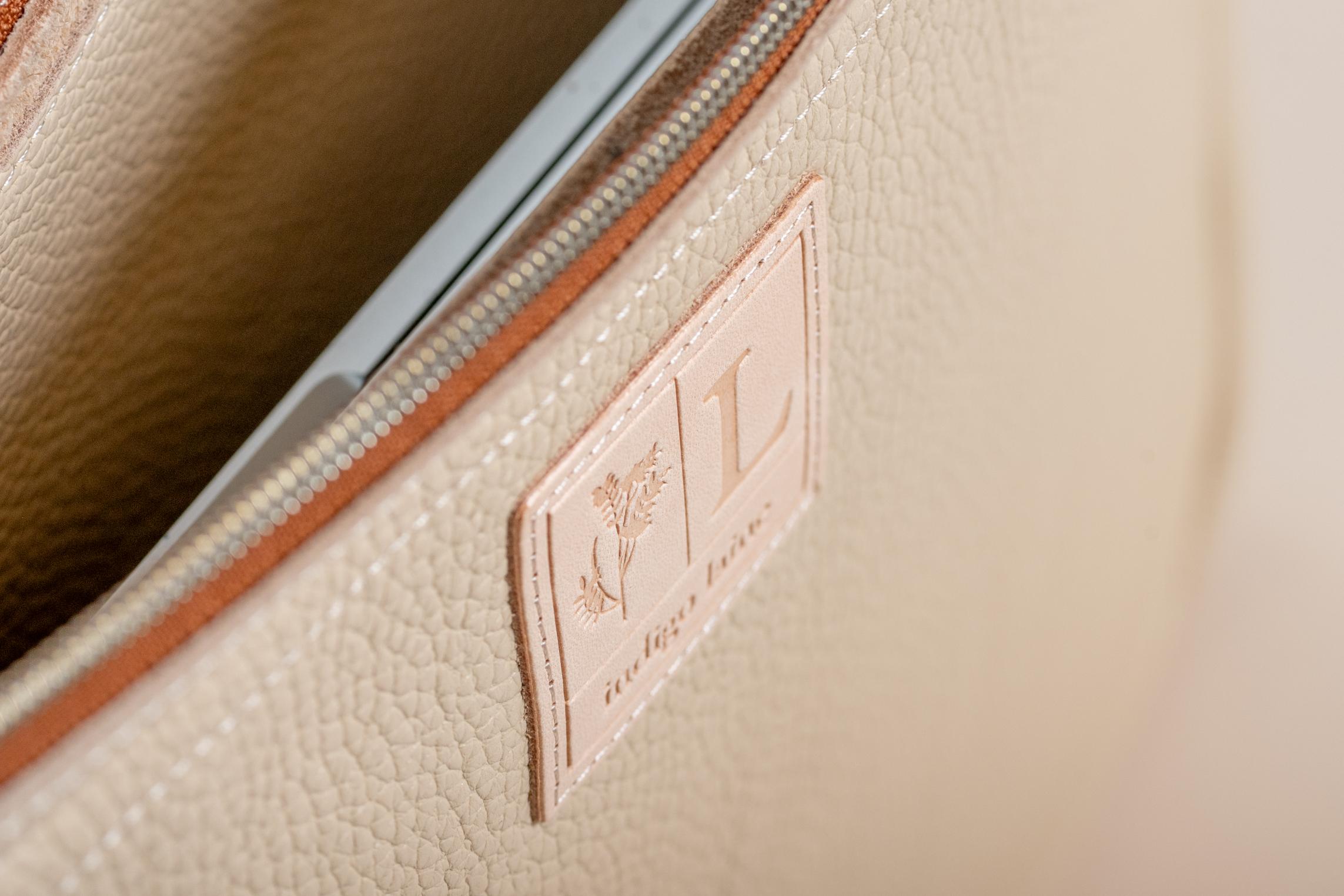 Close-up of Indigo Laine The Laptop Sleeve in Bone, showing the Indigo Laine logo and zipper