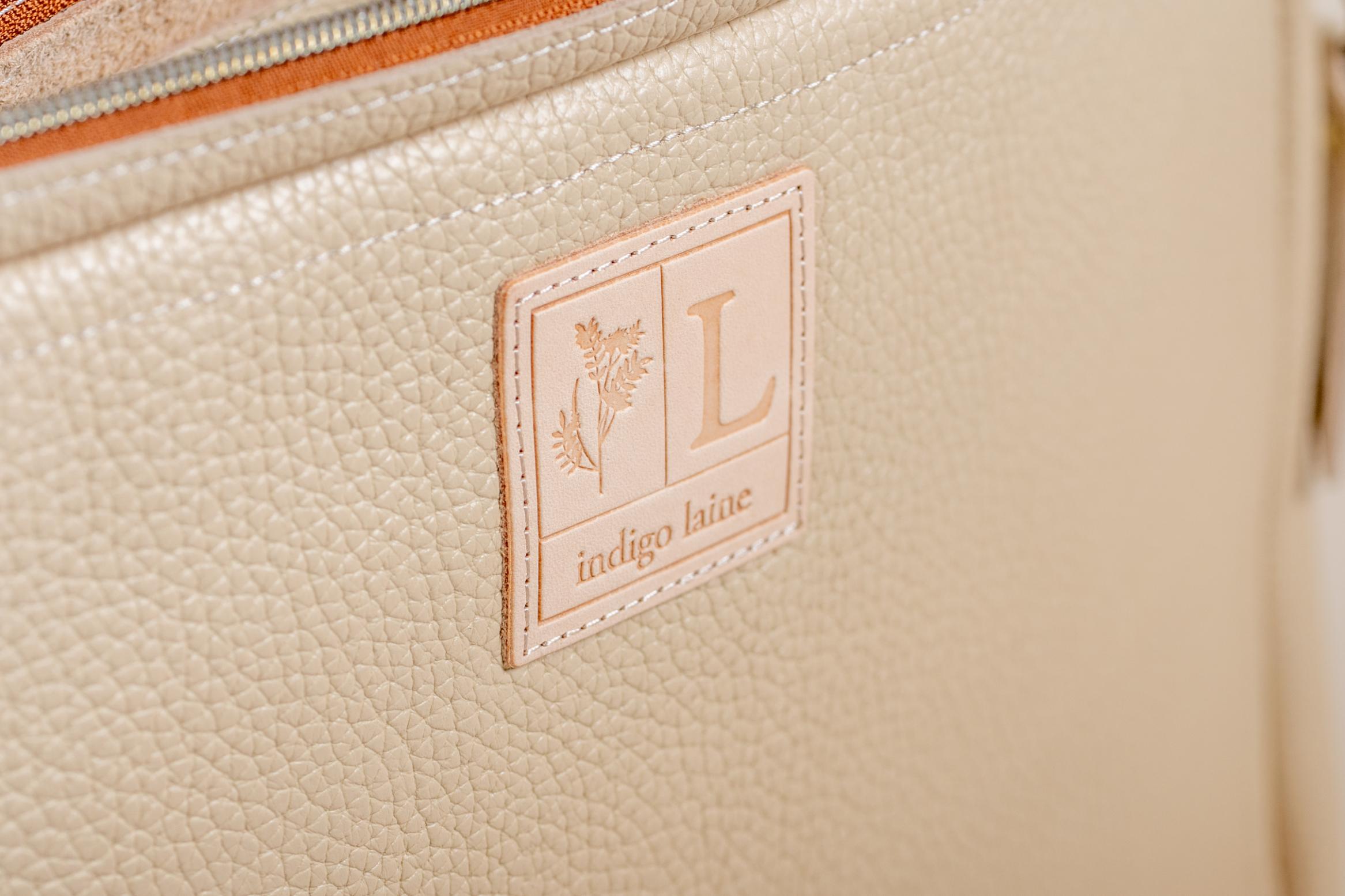 Close-up of Indigo Laine The Laptop Sleeve in Bone, showing the Indigo Laine logo