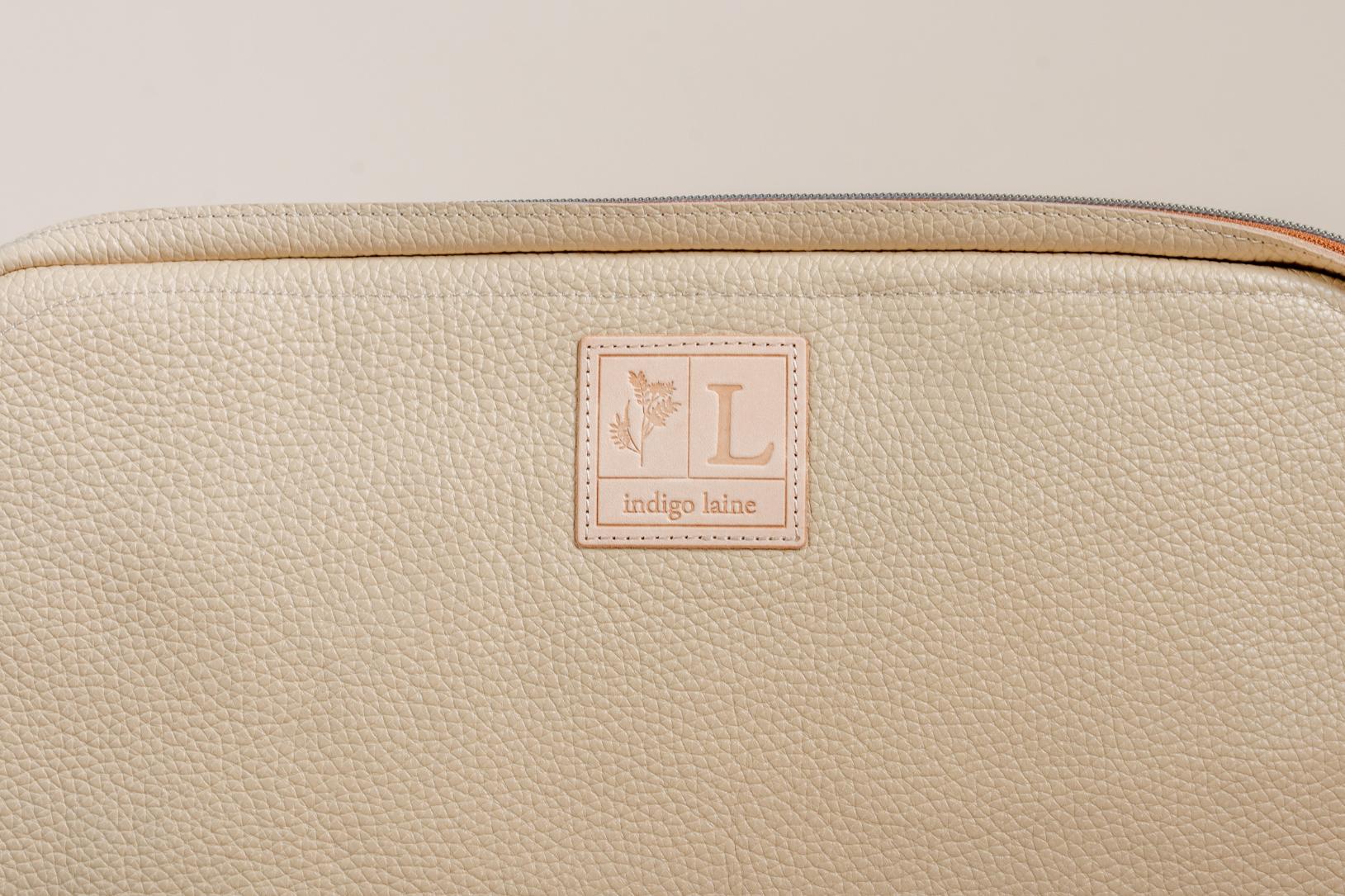 Close-up of Indigo Laine The Laptop Sleeve in Bone, showing the Indigo Laine log and zipper