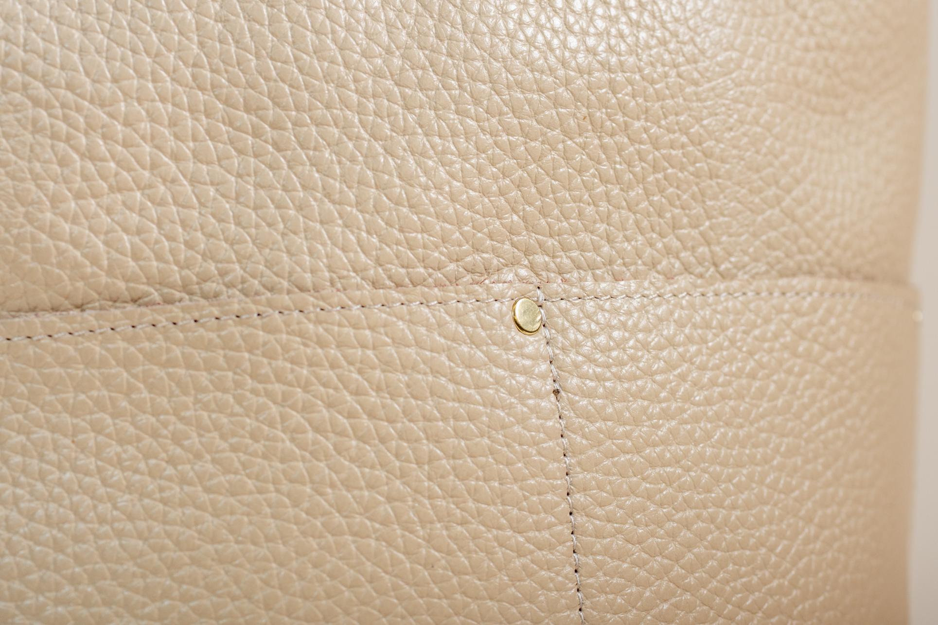 Close-up of cream leather grain, stitching, and rivet detail