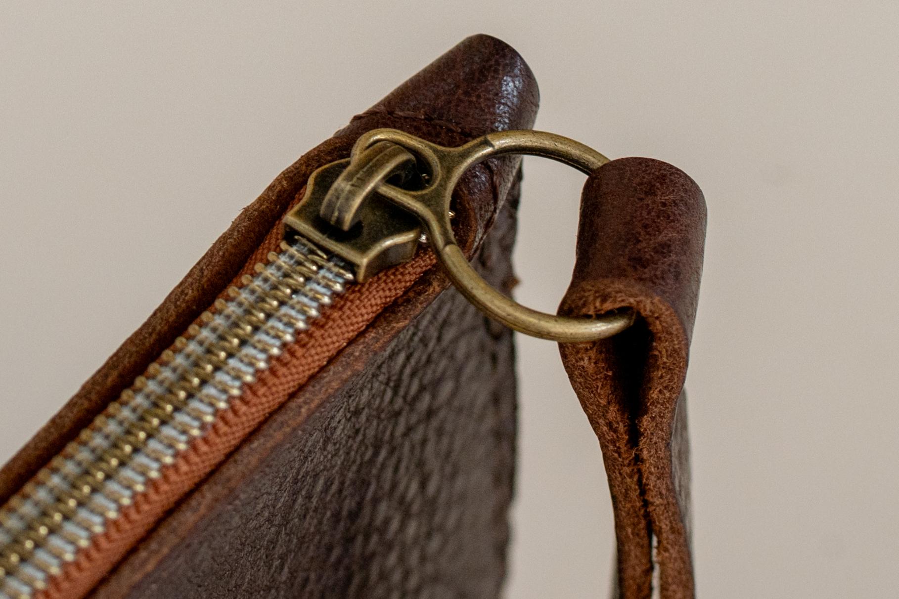 Close-up of The Cami wallet's brass clasp hardware in tobacco leather