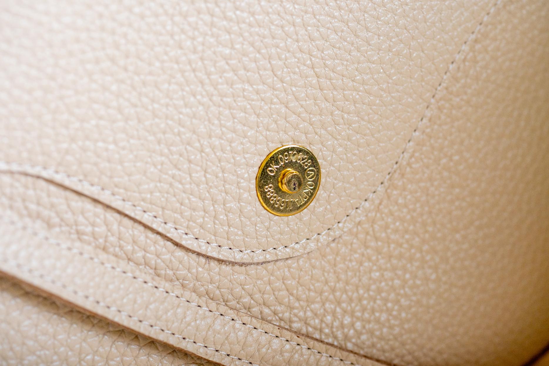 Close-up of The Shelly Crossbody's gold snap closure in cream