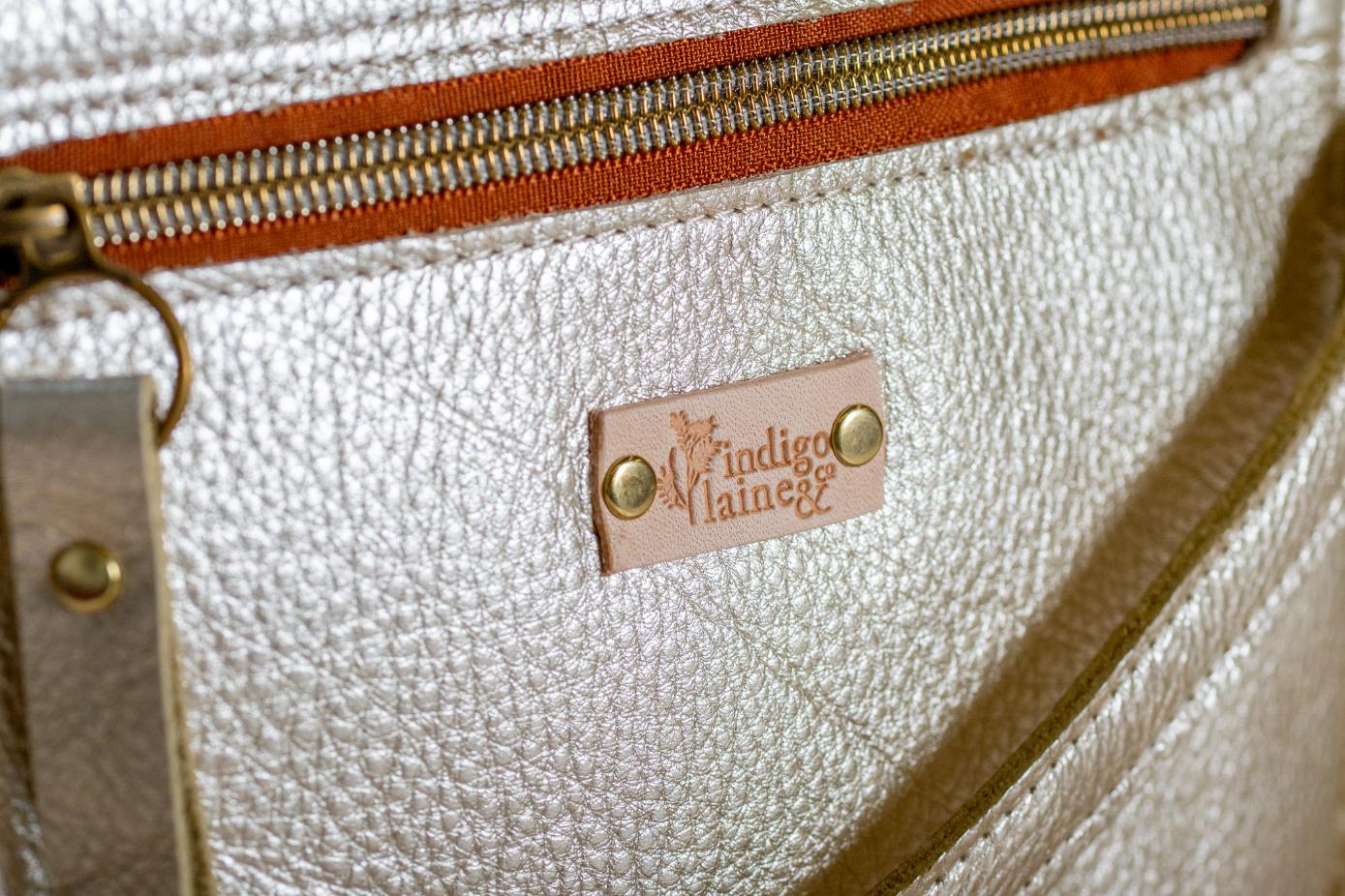 Close-up of The Shelly Crossbody's zip pocket and brand tag