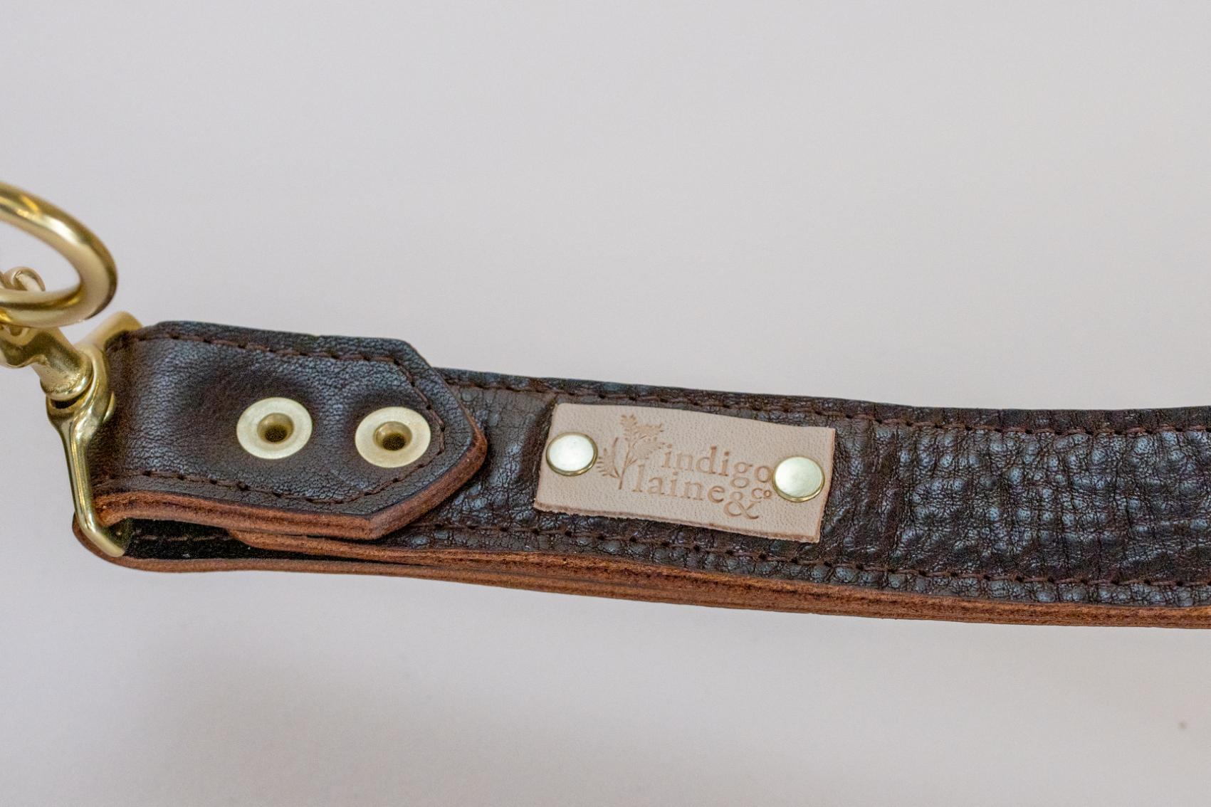 Close-up of The Sloane's wrist strap and brand tag in dark brown