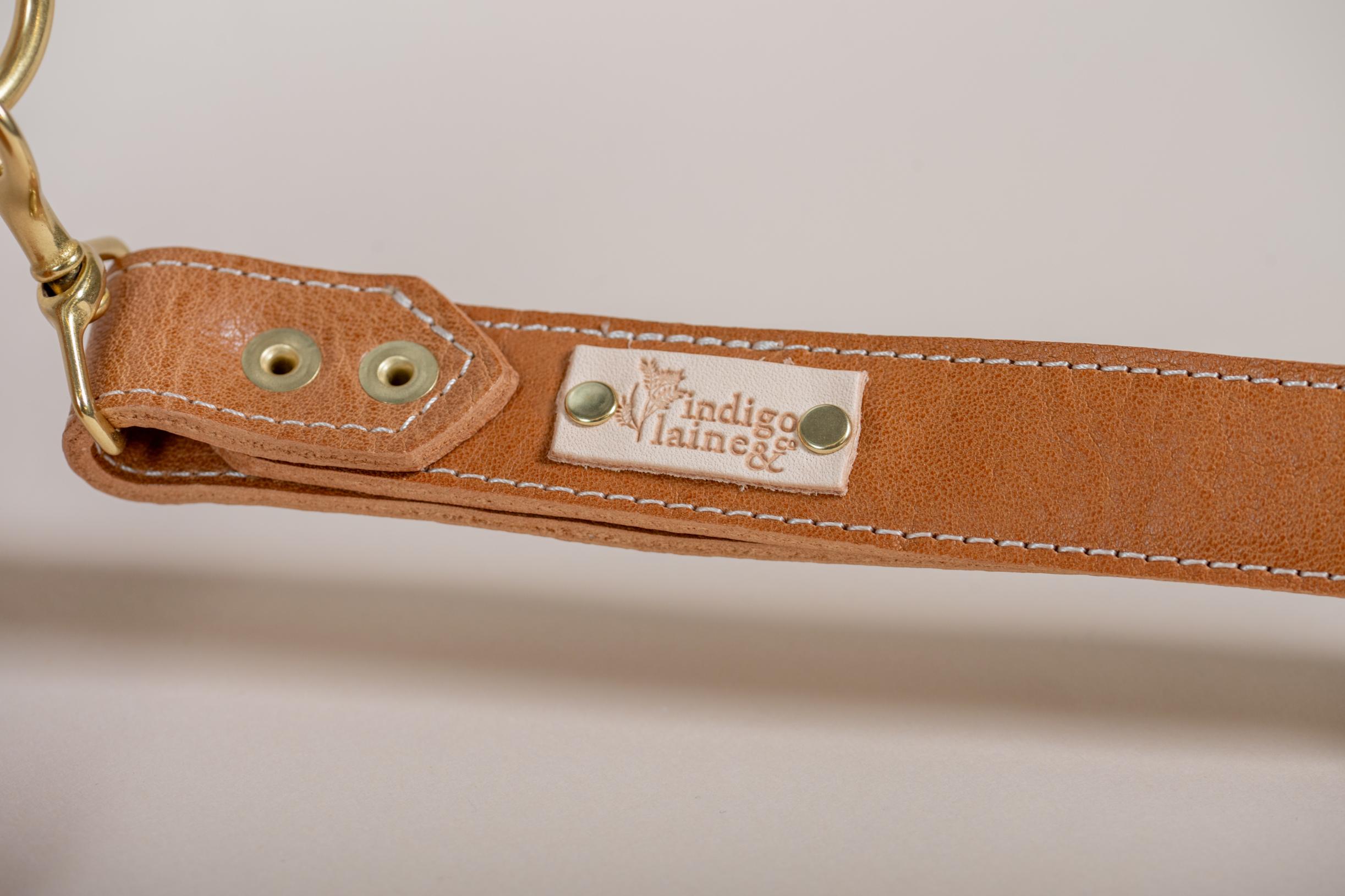 Close-up of The Sloane's wrist strap and brand tag in camel