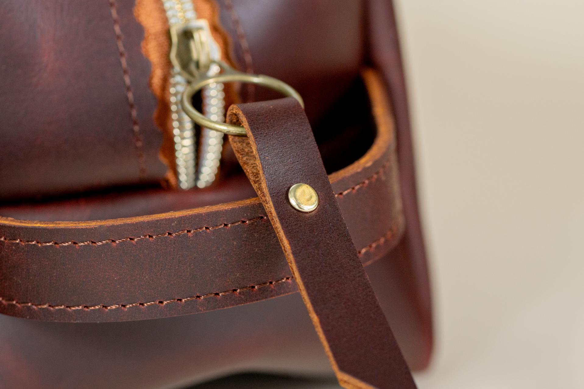 Close-up of Indigo Laine The Toiletry Kit in Tobacco, showing the 		Strong leather handle