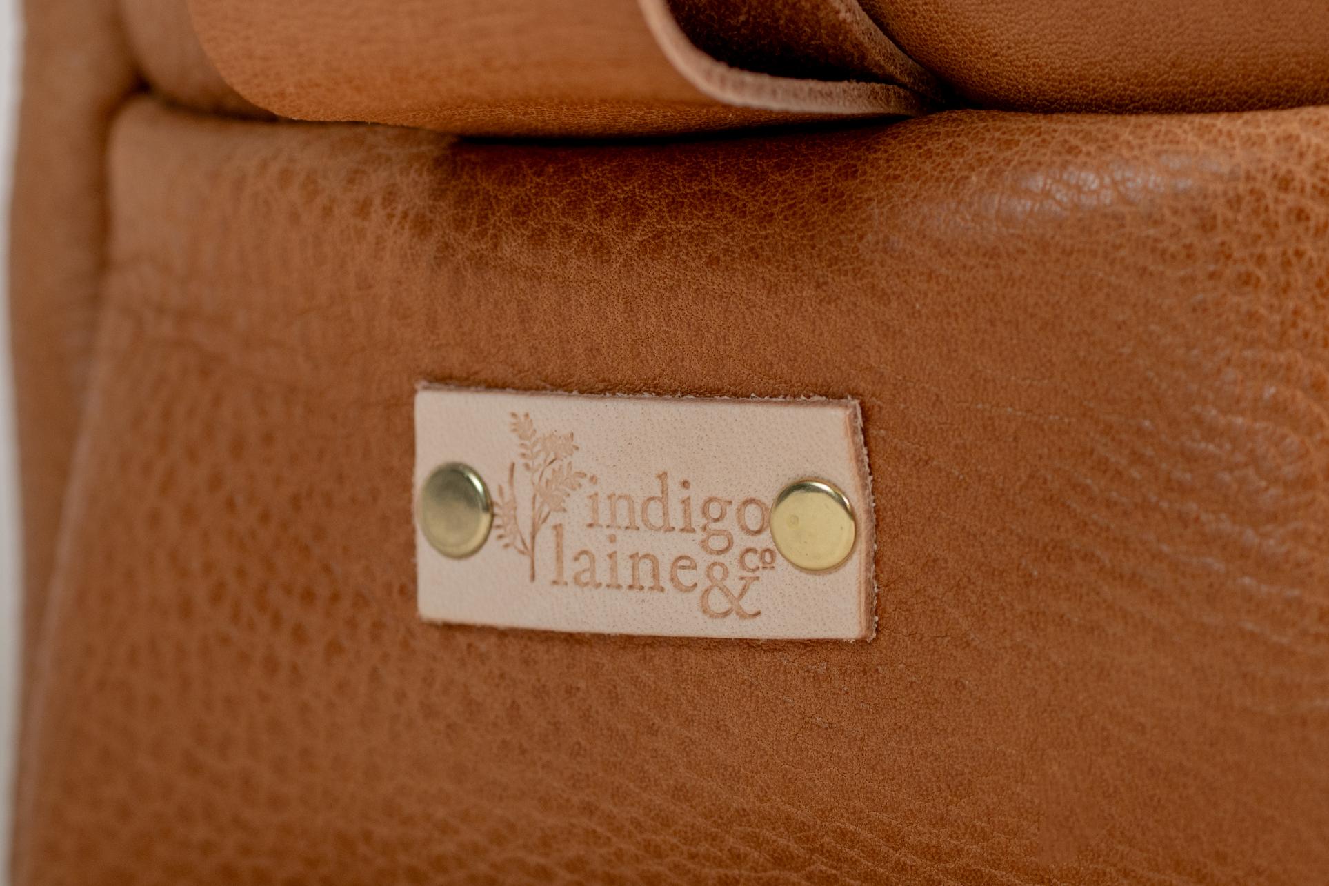 Close-up of Indigo Laine The Toiletry Kit in Camel, showing the Indigo Laine logo
